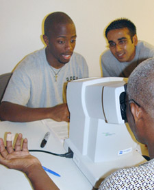 Reginald St. Hilaire, left, and Neil Masters, both first year medical students, work with a community member to test his vision during the Little Haiti Community Health Fair October  21.